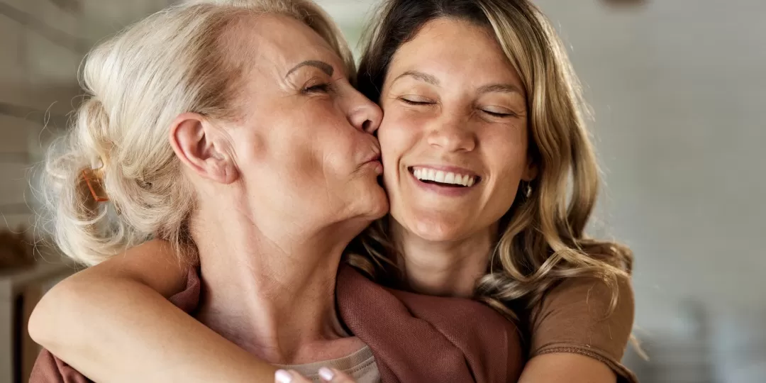 Idosa e adulta se abraçam felizes