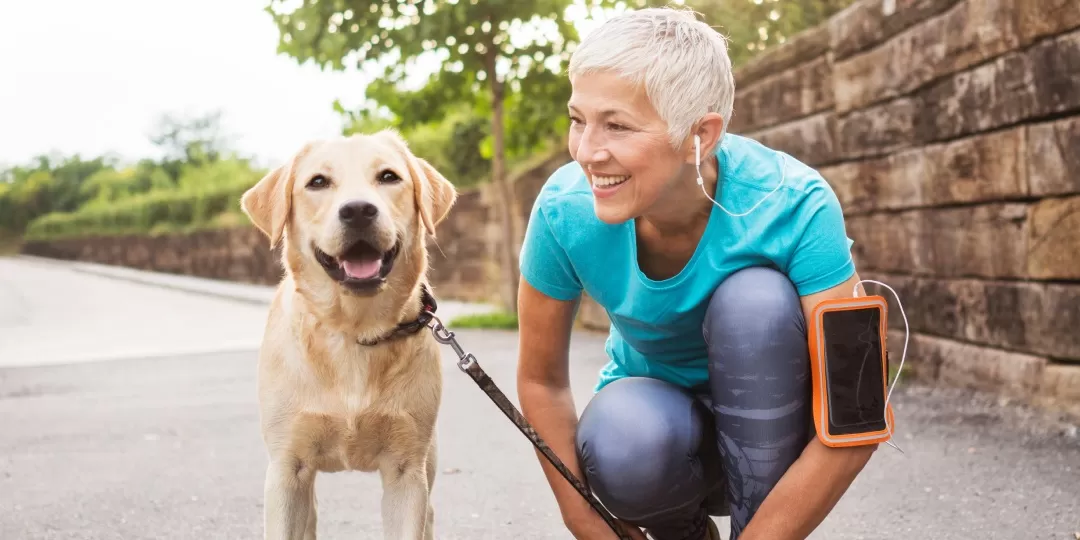 Mulher idosa ao ar livre se exercitando com cachorro ao lado